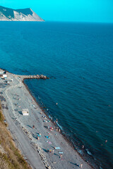 Vacationing tourists on the stone coast of a beautiful sea. A crowd of people resting on the beach near the blue sea.