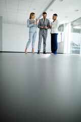 Business man and women standing in modern interior, talking to each other. Partners meeting concept.