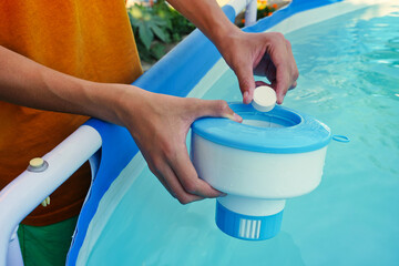 White mini chlorine tablet in the hand of a service worker for disinfection of swimming pools. The beginning of the swimming season is hot summer. - obrazy, fototapety, plakaty