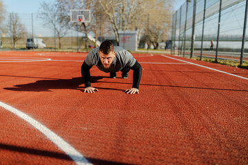 Photo of a young athletic man doing push ups outdoors.