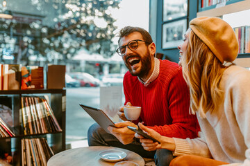 Young couple is laughing while sitting in bookstore cafe and having coffee.
