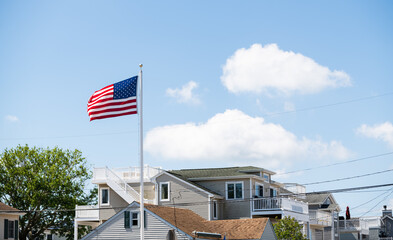 American flag waving in the wind in front of beach houses celebrating the 4th of July, Long Beach...