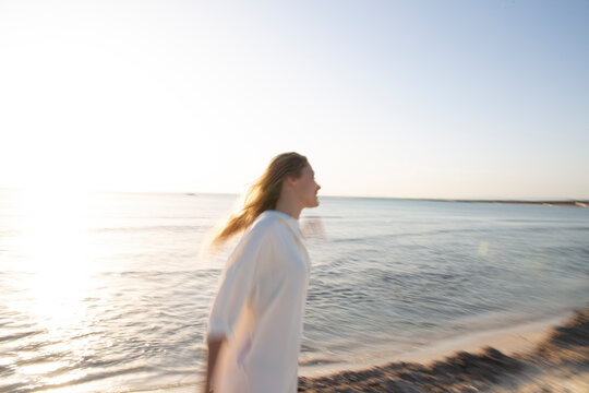 Long-haired blonde Woman standing on the beach looking into the distance