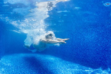 Underwater shot of man jumping in the pool.
