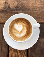 Macchiato with foam in the form of a heart on a wooden table