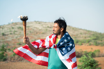 young athlete holding sports flame torch and looking with USA or American flag on shoulder.