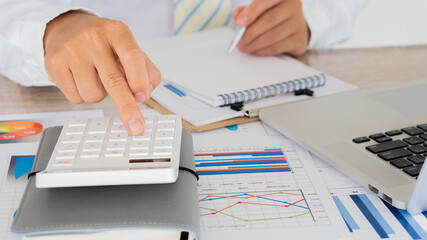 Businessman looking at the company's financial graph document for analysis and guidance. Asian business accountant or banker is calculating savings, finance and economy concepts through financial conc