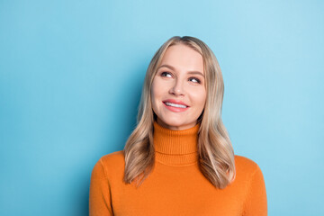 Photo of adorable cute young lady wear orange sweater looking empty space isolated blue color background