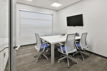 Modern office business conference room with office chairs, white table, and tv