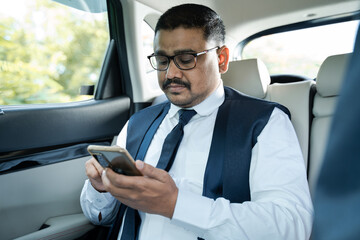 young Businessman busy using mobile phone on moving car - Concept of successful people, technology and happiness.