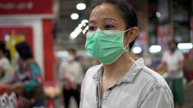 Asian woman wearing mask in supermarket queue social distance