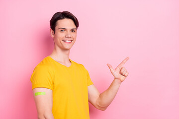 Profile side photo of young guy happy point finger empty space advice choice band aid vaccination isolated over pink color background