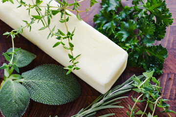 stick of butter surrounded by green herbs