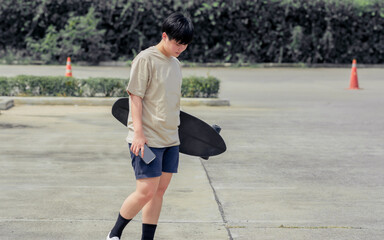 Portrait adult sportive Asian skater wearing hipster shirt with shorts, smiling with happiness,...