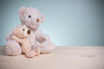 Big and little brown teddy bears sitting huggy show love, happiness on an old wooden table with copy space. Concept family, love, and valentines festival.