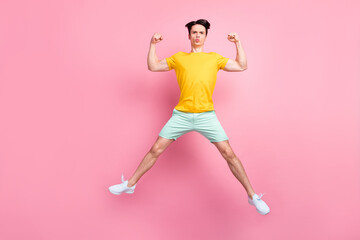 Fototapeta na wymiar Photo of sporty strong energetic guy jump show biceps wear yellow t-shirt isolated on pink background