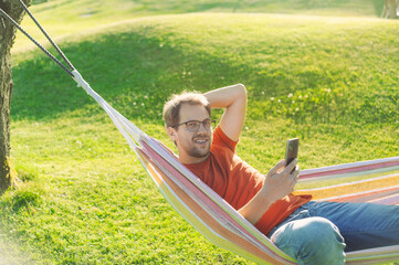 portrait of attractive nerd   man with glasses in the park with green lawn have a nice sunset in ...