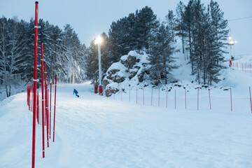 a snowboarder rolls down the ski slope in the evening under artificial lighting