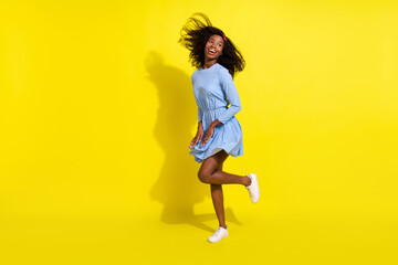 Fototapeta na wymiar Full length body size photo of dancing girl in blue dotted dress looking empty space isolated on bright yellow color background