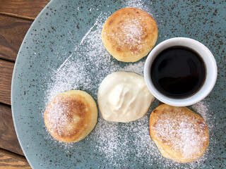 Сurd cakes with sour cream and maple syrup sprinkled with powdered sugar
