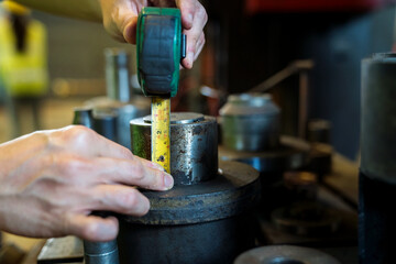 Hand using a steel tape measure. Industrial worker on quality using steel measuring tape measure length a part.