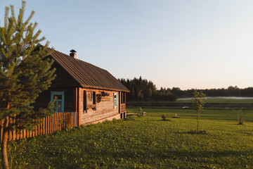 Naklejka na ściany i meble wooden european house in a picturesque countryside at sunset in summer