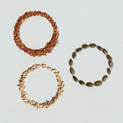 Circles made from different kinds of seeds on white background. Pumpkin seeds, sunflower seeds and linseed.