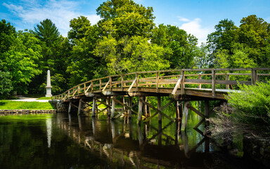 Fototapeta premium Old North Bridge at Minuteman National Historical Park in Concord, Massachusetts. Tranquil Nature Landscape with Landmark Bridge and Clean River. Peaceful American New England Image.