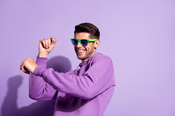 Portrait of attractive cheerful guy dancing having fun music club weekend isolated over purple...