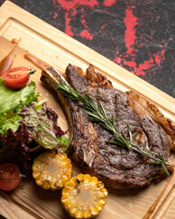 Luxury ribeye meat steak with rosemary. Tomahawk or t-bone steak. Soft focus. Close-up shot. Copy space. Vertical format.