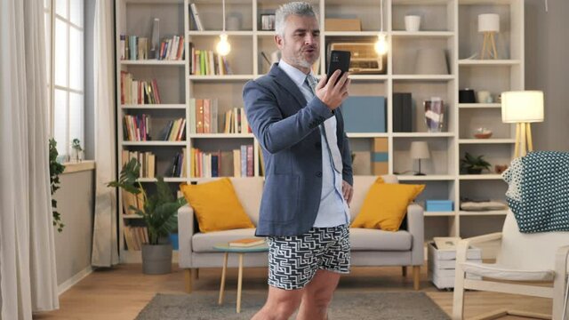 business man in underwear and shirt having a conference call,mature caucasian male works from home using mobile phone to make a work video call
