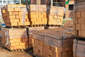 Bricks in pallets on a construction site. Construction Materials. Red brick for building a house.