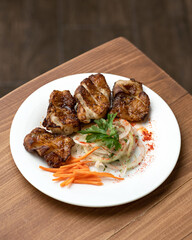 Fried juicy meat fillet with salad. Food plate on wooden table. Vertical format. Soft focus. Copy space.