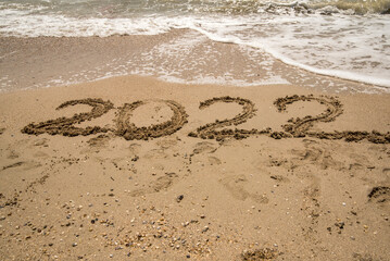the number 2022 is written on the sea sand