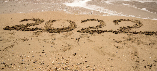 the number 2022 is written on the sea sand