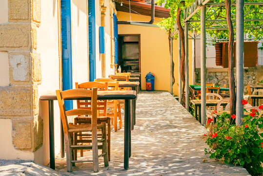 Chairs and tables in an outdoor cafe on a narrow street in Foini, Cyprus. Nobody.