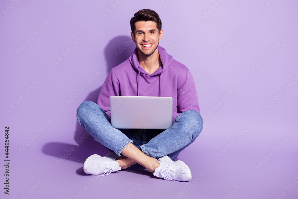 Poster portrait of attractive cheerful guy sitting lotus pose using laptop free time isolated over purple v