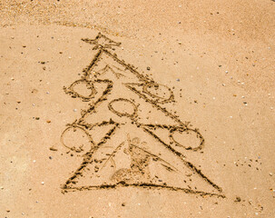 a Christmas tree is painted on the sea sand