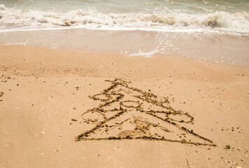 a Christmas tree is painted on the sea sand