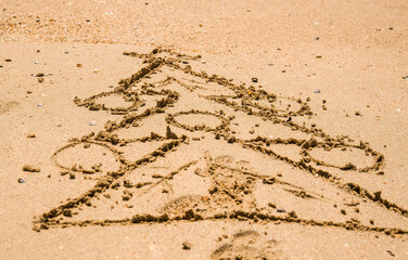a painted Christmas tree with a decoration on wet sea sand