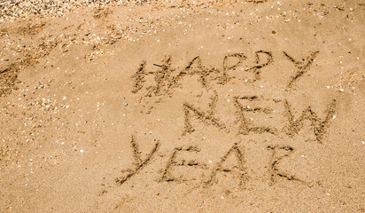 happy new year inscription on wet sea sand