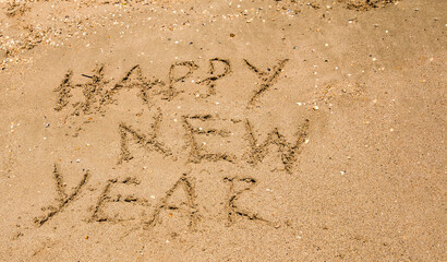 the text happy new year is written on wet sea sand