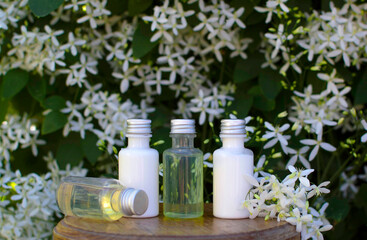 Obraz na płótnie Canvas Body care product in the shower and shampoo with white flowers on green background. The concept of daily skin care. A plastic bottle of shampoo with a floral fragrance. A simple example of a shampoo.