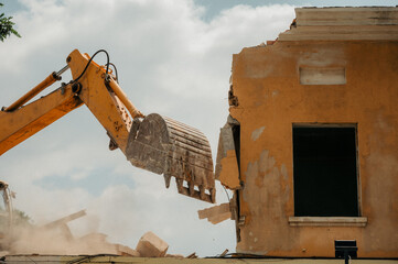 A construction bulldozer demolishes an old house on a clear day.
New construction site.