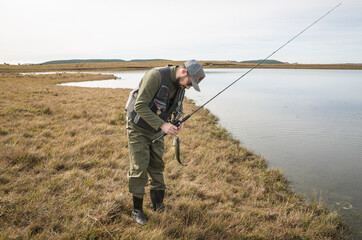 Fototapeta premium Sport fisherman fishing in lake on cloudy day.