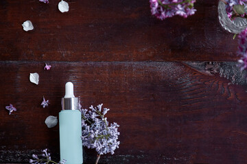 Dropper glass Bottle Mock-Up. Body treatment and spa. Natural beauty products. Template of turquoise anti aging serum droplet bottle in the lilac flowers. Natural wellness cosmetic product concept