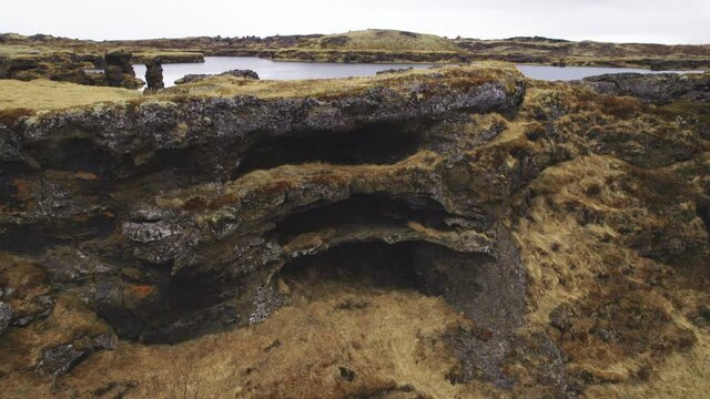 Drone Shot of Stone Formation in Iceland Covered In Moss and Withered Grass