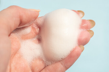 Female hand with white soapy foam on a blue background