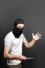an offender attack with a knife. Metal knife in the hand of caucasian man in black mask. forbidden...
