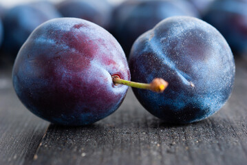 plums on black wood table, front view